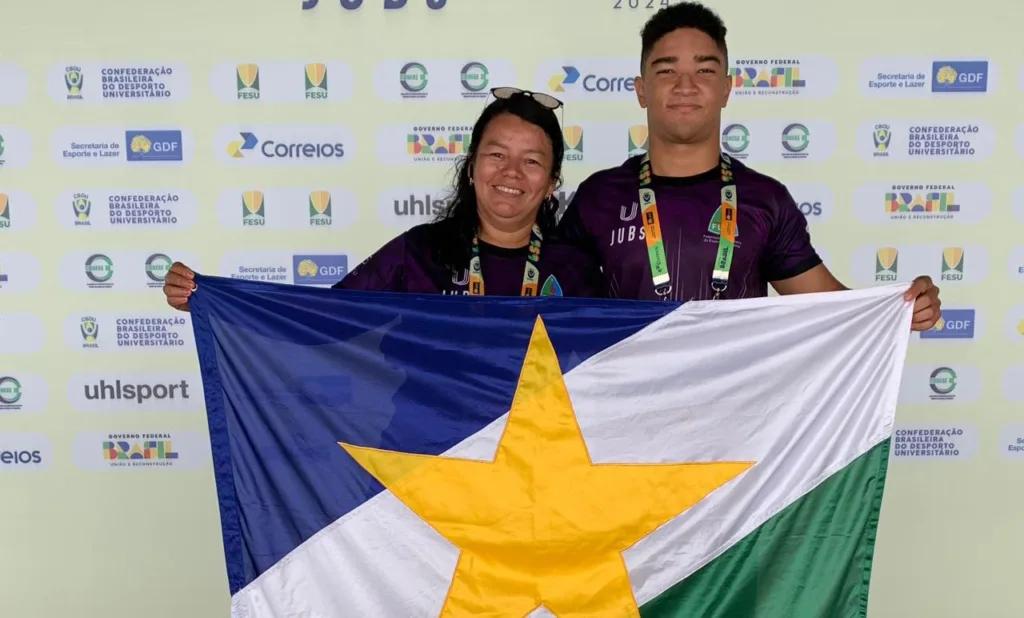 Professora Teca Marinho e atleta Kauã Santos posam com a bandeira de Roraima. (Crédito: Aquática Marinho)