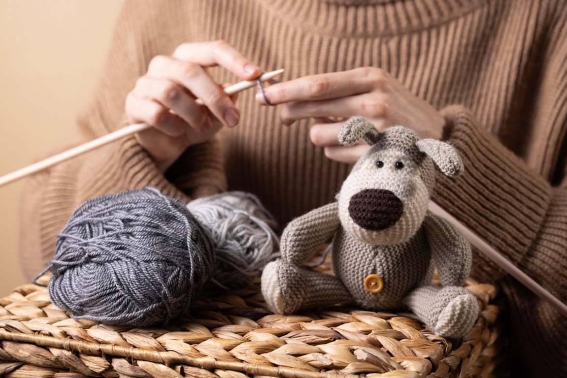 Woman knitting near handmade crochet dog toy. Warm and creative scene about slow living and crafting.