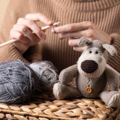 Woman knitting near handmade crochet dog toy. Warm and creative scene about slow living and crafting.