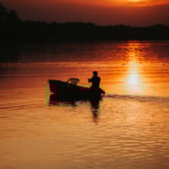 Silhueta de um pescador no lago durante o pôr-do-sol. Foto de wirestock/Freepik
