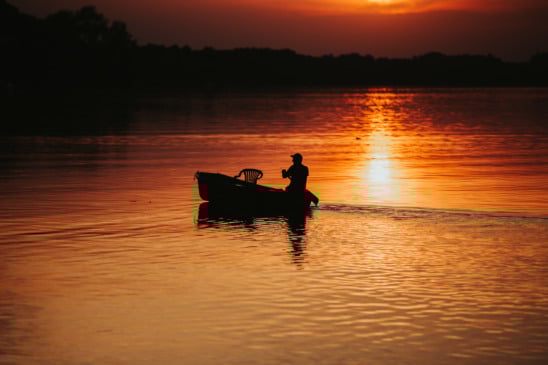 Silhueta de um pescador no lago durante o pôr-do-sol. Foto de wirestock/Freepik
