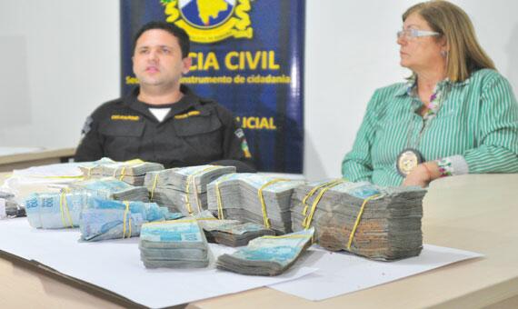 Delegados apresentaram o dinheiro que estava enterrado no quintal da casa de estelionatário (Foto: Rodrigo Sales)