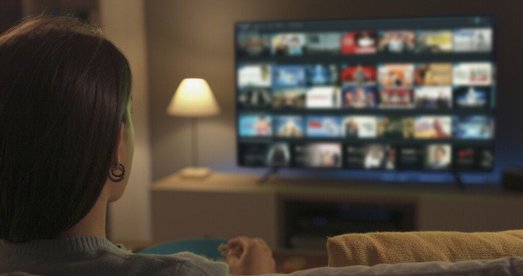 Young woman relaxing on the couch at home and watching videos on demand on her TV, entertainment concept Young woman relaxing on the couch at home and watching videos on demand on her TV, entertainment concept